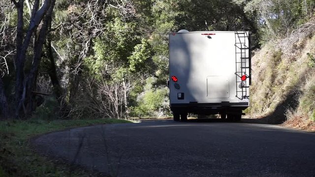 RV motorhome appearing on a wooded curvy road in California.