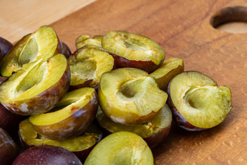 Sliced tasty juicy plums on wooden background