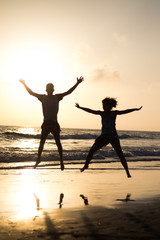 Fototapeta premium silhouette of two person jumping on the beach