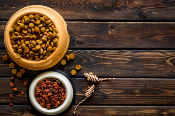 Cat food in bowl and toys on wooden background top view copyspace