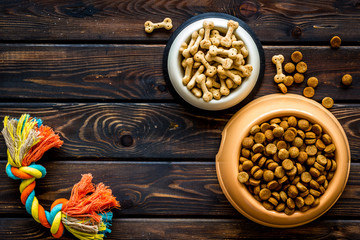 Pet food in bowl and tools for grooming on wooden background top view space for text