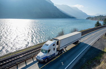Big rig semi truck transporting cargo in refrigerator semi truck running on the road along Columbia...