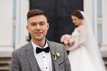 Wedding. Portrait of elegant groom on beautiful bride in white wedding dress background