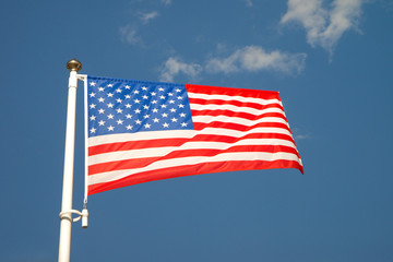 United States flag waving on the wind. Bright flag of America on the mast in sunny day and and blue skies. Bottom view.