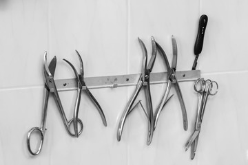 medical instruments hanging on a suspension mounted on a wall, bw