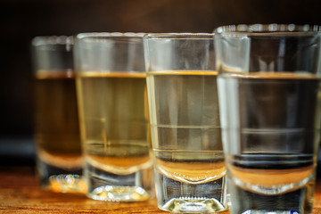 Several glasses of brazilian cachaça isolated on rustic wooden background, variations and types of brazil cachaça, typical drink from brazil.