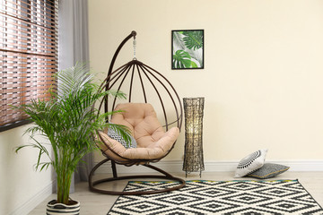 Comfortable swing chair with pillows in room interior