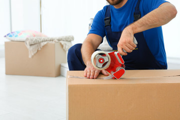 Young worker packing box in room, closeup. Moving service