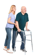 Caretaker helping elderly man with walking frame on white background