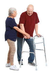 Elderly woman helping her husband with walking frame on white background