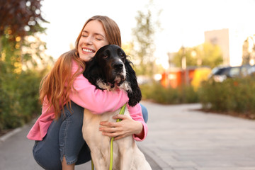 Young woman hugging her English Springer Spaniel dog outdoors. Space for text