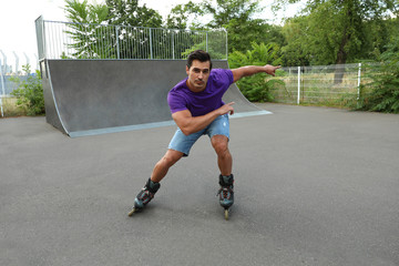 Handsome young man roller skating in park