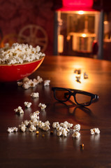 Spilled Popcorn in an Antique Red Wooden Bowl with 3D Movie Glasses on a Table with Popcorn Machine