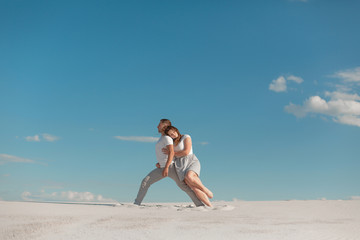 Romantic couple dancing in sand desert at blue sky background