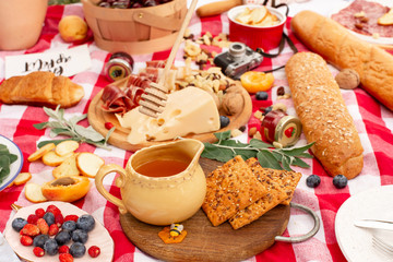 Stylish picnic on the green lawn. Fresh croissants and a teapot with tea on a bedspread near a wicker female hat. Instagram content