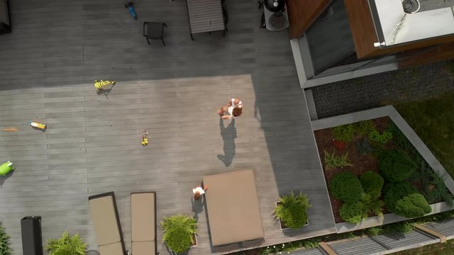 Aerial: Young mother with her baby boy son brothers during their free time at their garden - Family values warm color summer scene drone top shot from above