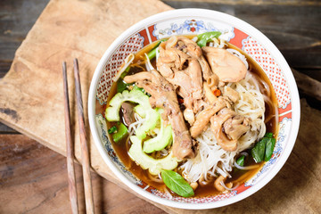 Rice noodles soup with stewed chicken wing and feet in a bowl with chopsticks