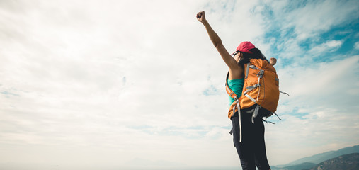 Successful hiker outstretched arms at seaside mountain top cliff edge