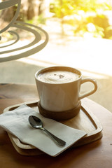 The ceramic cup of hot cappuccino coffee on the wooden table in the restaurant or coffee shop. natural light. morning hot drink cafe shop.