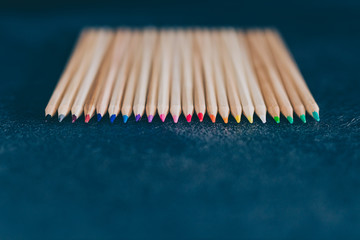set of coloured pencils on desk on dark background shot at shallow deph of field