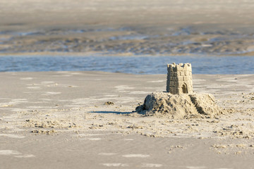 Detailed sand castle on the beach with a tidal pool in the background