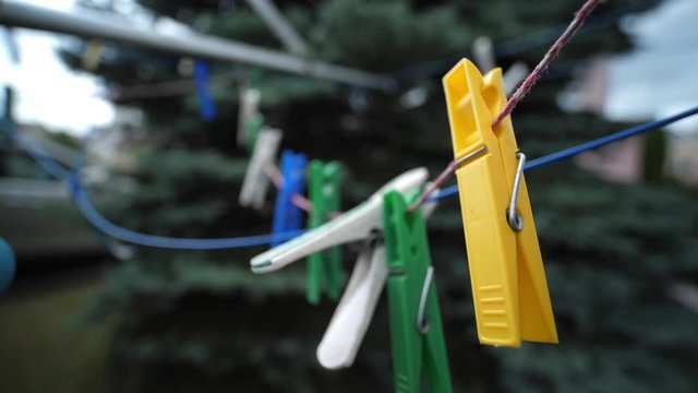 Colorful laundry Pegs clothes pins hanging on washing line outdoors. Windy day in Slow motion