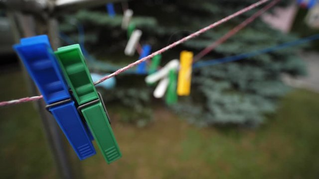 Colorful laundry Pegs clothes pins hanging on washing line outdoors. Windy day in Slow motion
