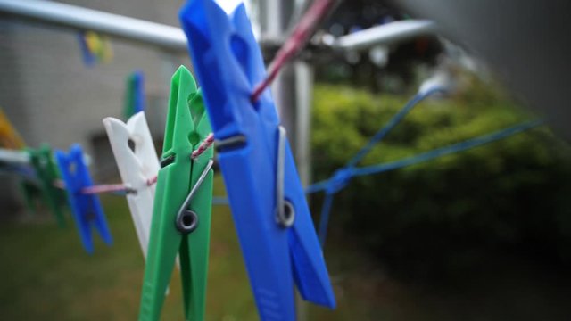Colorful laundry Pegs clothes pins hanging on washing line outdoors. Windy day in Slow motion