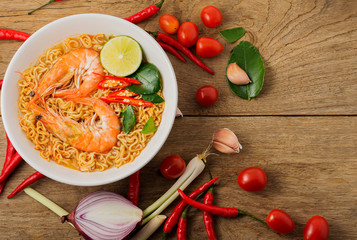 Instant noodles, spicy shrimp soup, spicy, spicy, with Thai spices placed on an old wooden table.