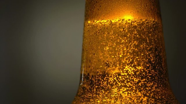 Macro close-up Bottle of beer with water drops on black background. Bubbles. 4K UHD video footage 