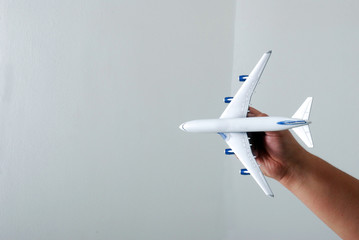 A man hand holding a miniature aeroplane against white background