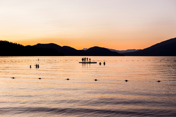 Silhouettes of people standing on a dock in a lake at sunset