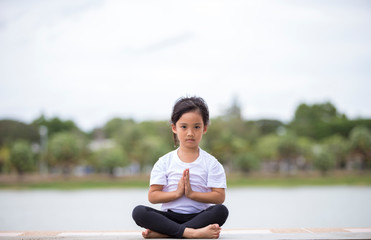 Fototapeta premium beautiful little asian child girl doing yoga in the public park.