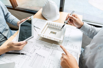 Real-estate concept, Two engineer and architect discussing blueprints data working and digital...