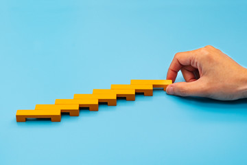Business concept for growth success process, hand stacking wood block as step stair