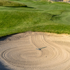 Obraz premium Square Bunker and fairway of a golf course with homes mountain and sky background