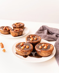 Homemade chocolate muffins with topping and walnuts on white table