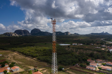 Mobile Antenna in a small city surrounding by small houses and rocks 