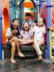 Happy Asian kids sitting at playground together in the park outdoor.