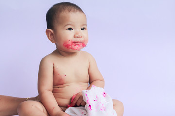 asian cute baby girl eating red dragon fruit. newborn baby on white background