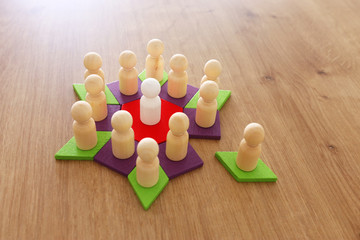 business concept image of tangram puzzle blocks with people figures over wooden table ,human resources and management concept