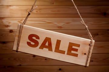 Wooden signboard with the words SALE on a rough rope on a beautiful wooden background