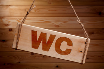 Wooden signboard with the words WC on a rough rope on a beautiful wooden background