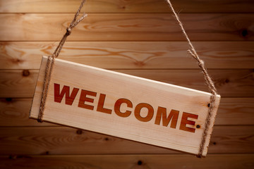 Wooden signboard with the words WELCOME on a rough rope on a beautiful wooden background