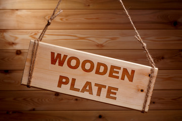 Wooden signboard with the words wooden plate on a rough rope on a beautiful wooden background