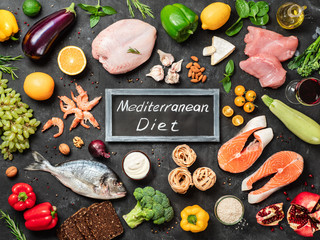 Mediterranean diet concept. Top view of food ingredients and chalkboard with words Mediterranean Diet in center. Dark background. Flat lay.