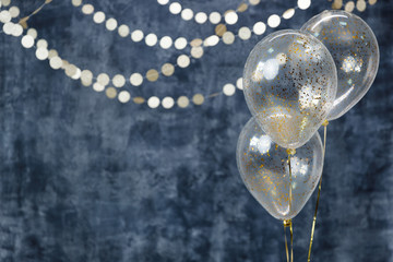 Three balloons with confetti and gold garlands on a smoky dark blue background. Birthday and...
