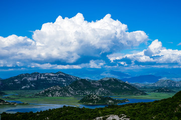Fototapeta na wymiar Montenegro, Tree covered black mountains surrounded by waters of skadar lake national park, the border to albania from above