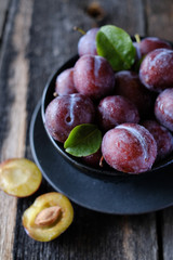 Fresh violet plums at dark wooden table background