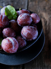 Fresh violet plums at dark wooden table background